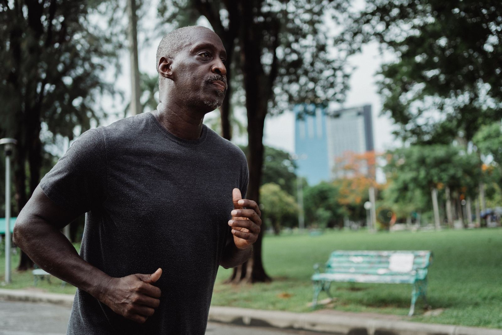 Un homme court sur un chemin de parc sous les arbres.