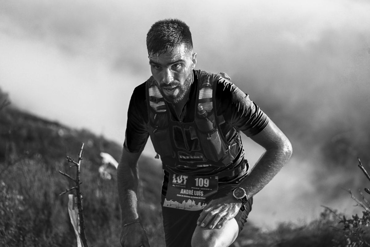 Un participant à un trail se penche vers l’avant dans une montée pierreuse.