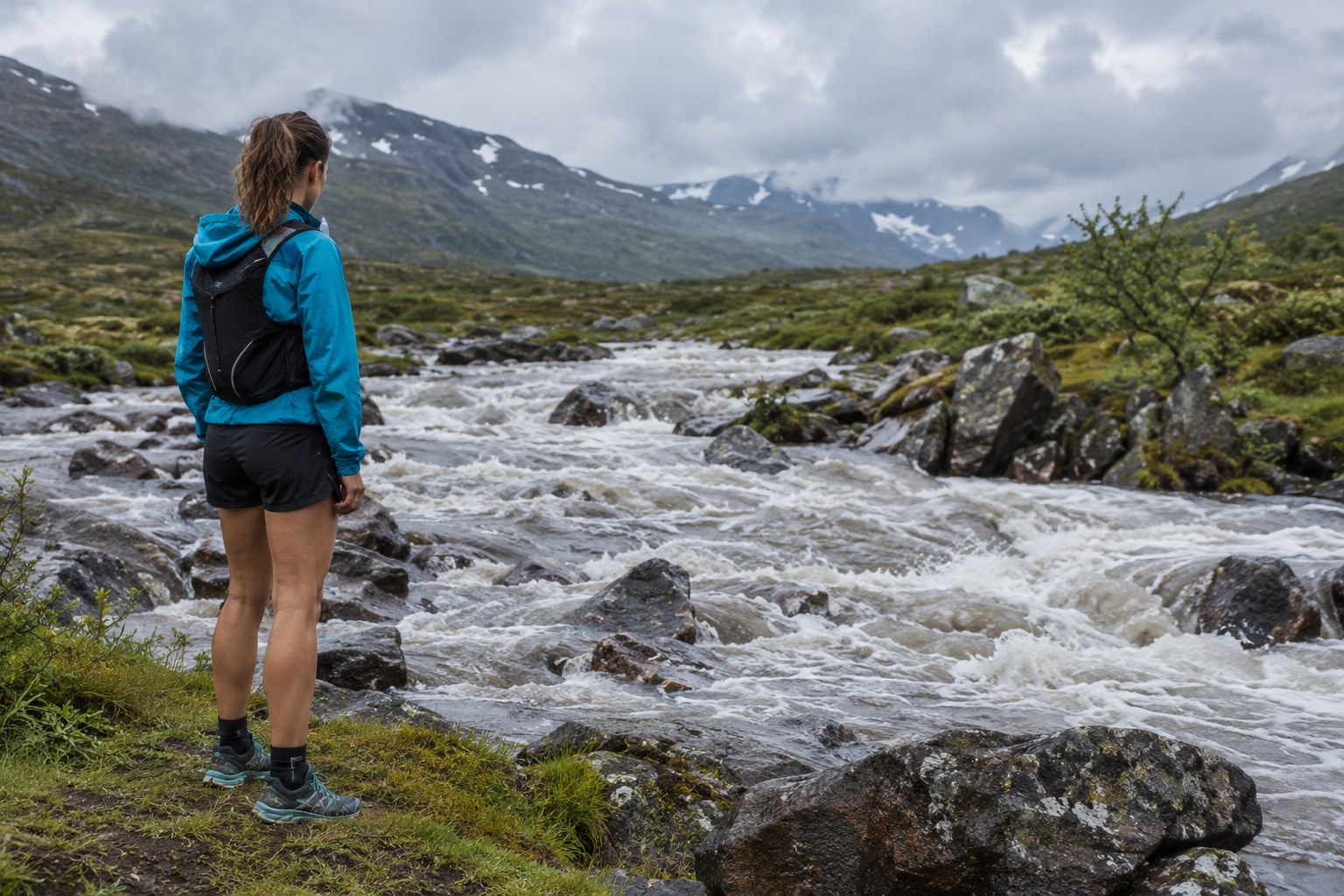 Un coureur s’arrête en retrait d’un passage d’eau gonflé.
