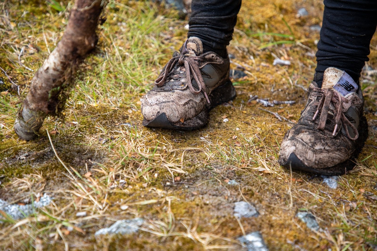 La boue recouvre le dessus et les lacets de deux chaussures de plein air.