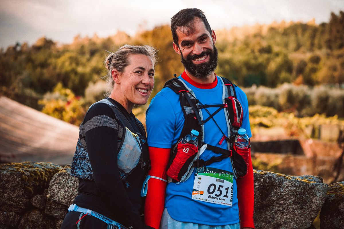 Deux participants à un trail portant un gilet d’hydratation se tiennent ensemble dehors.