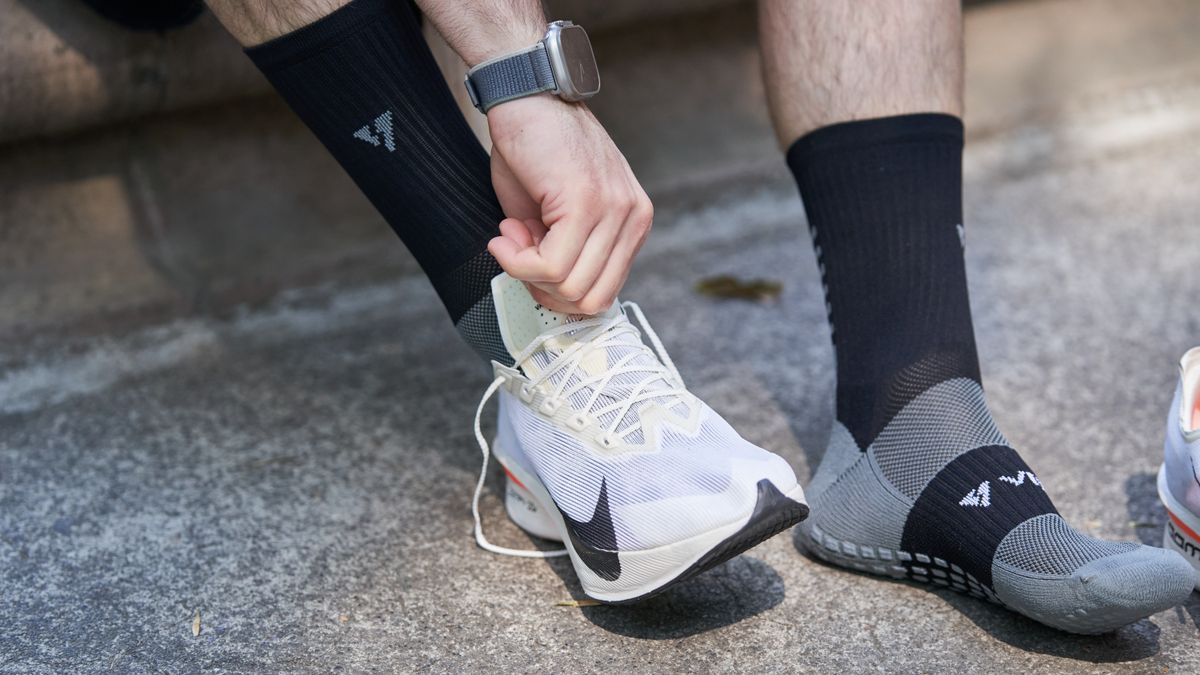 Un coureur essaie une chaussure blanche avec des chaussettes de sport.
