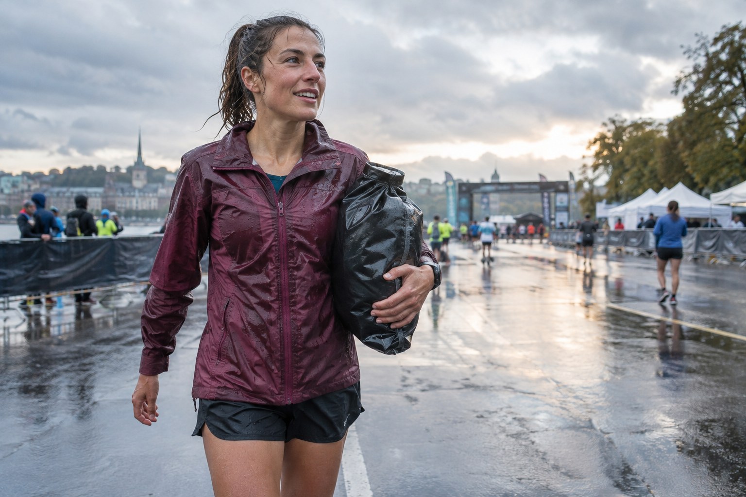 Un coureur tient un sac de vêtements secs dans une aire d’arrivée mouillée.