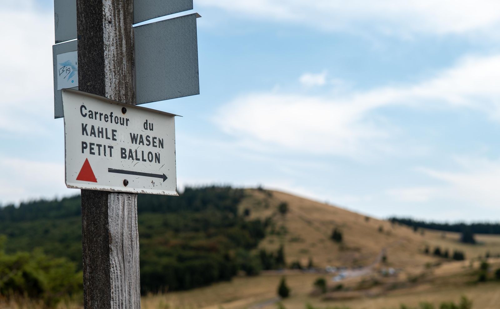 Un panneau vers Kahle Wasen et le Petit Ballon devant un paysage ouvert des Vosges.